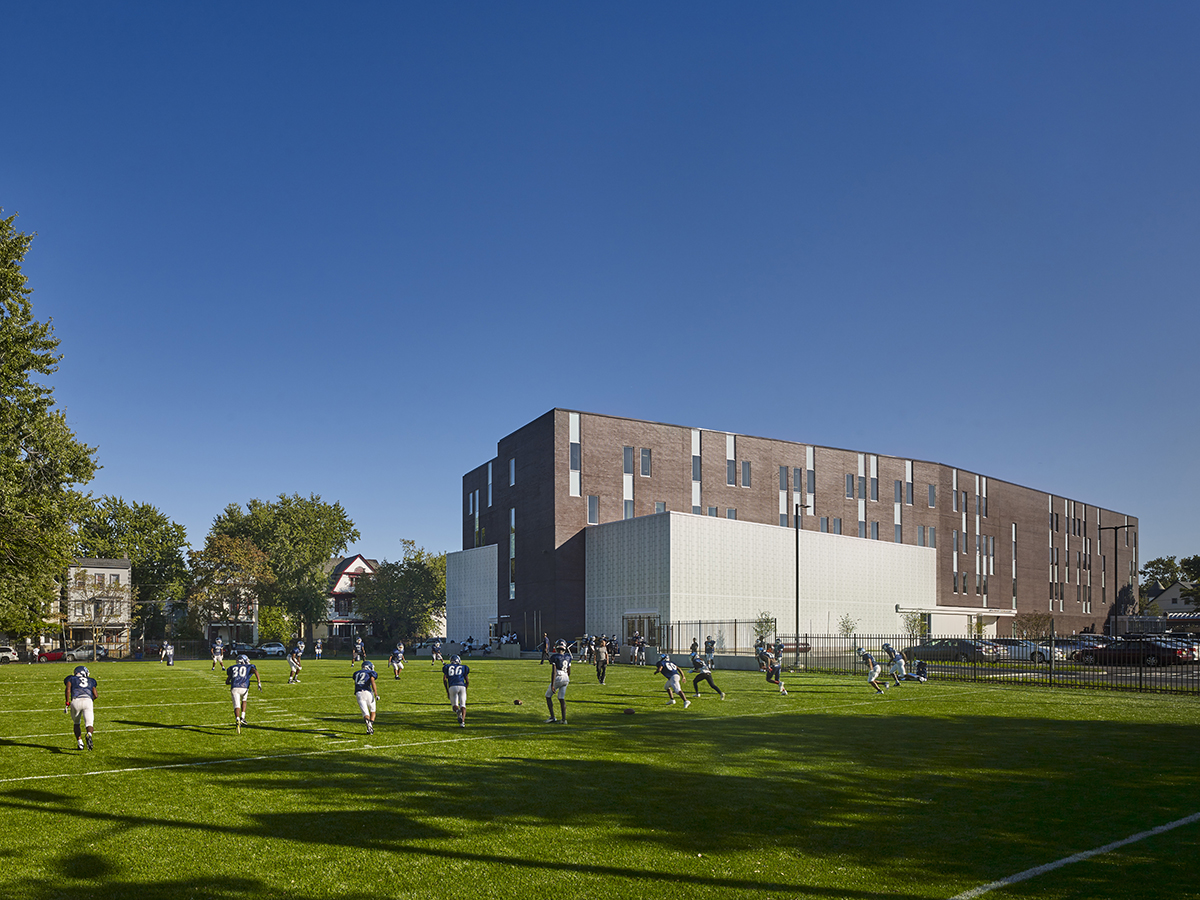 Football players on field at KIPP Newark Collegiate Academy with brick building in background featuring Kalwall wall system