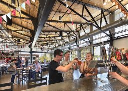 Group of friends enjoys beers at New Belgium Brewery with Kalwall facade application as backdrop