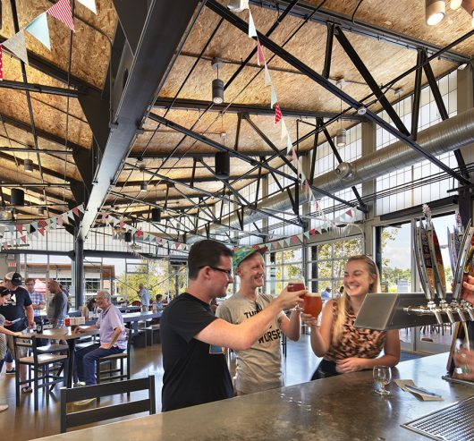 Group of friends enjoys beers at New Belgium Brewery with Kalwall facade application as backdrop