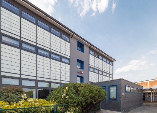 Featherstone High School exterior featuring Kalwall unitized curtain wall system for view to outside with flowers in front