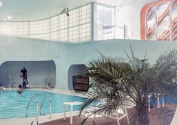 People in swimming pool and on a workout bike in room with gray walls with Kalwall translucent facade panels above