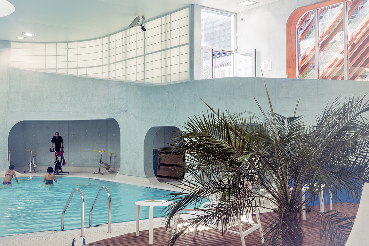 People in swimming pool and on a workout bike in room with gray walls with Kalwall translucent facade panels above