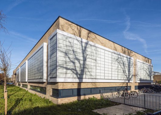 Segbroek College exterior set against blue sky with Kalwall translucent FRP panels wrapping sections of brick building