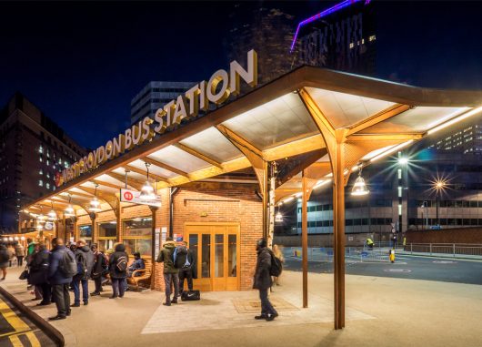 Exterior of West Croydon Bus Station at night with a Kalwall canopy system for a brick building, with a cityscape background