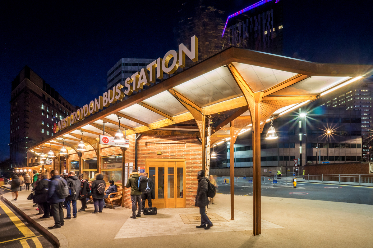 Exterior of West Croydon Bus Station at night with a Kalwall canopy system for a brick building, with a cityscape background