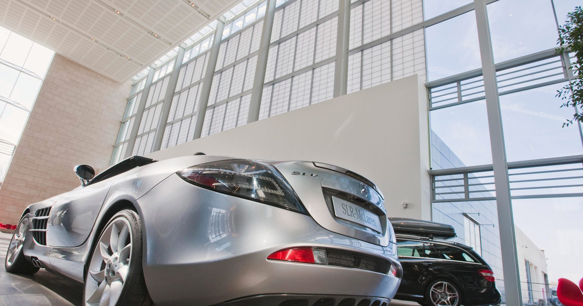 Mercedes Benz facility interior looking at two cars with Kalwall wall panel facade offering translucent daylighting above