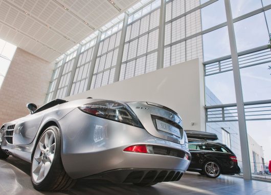 Mercedes Benz facility interior looking at two cars with Kalwall wall panel facade offering translucent daylighting above