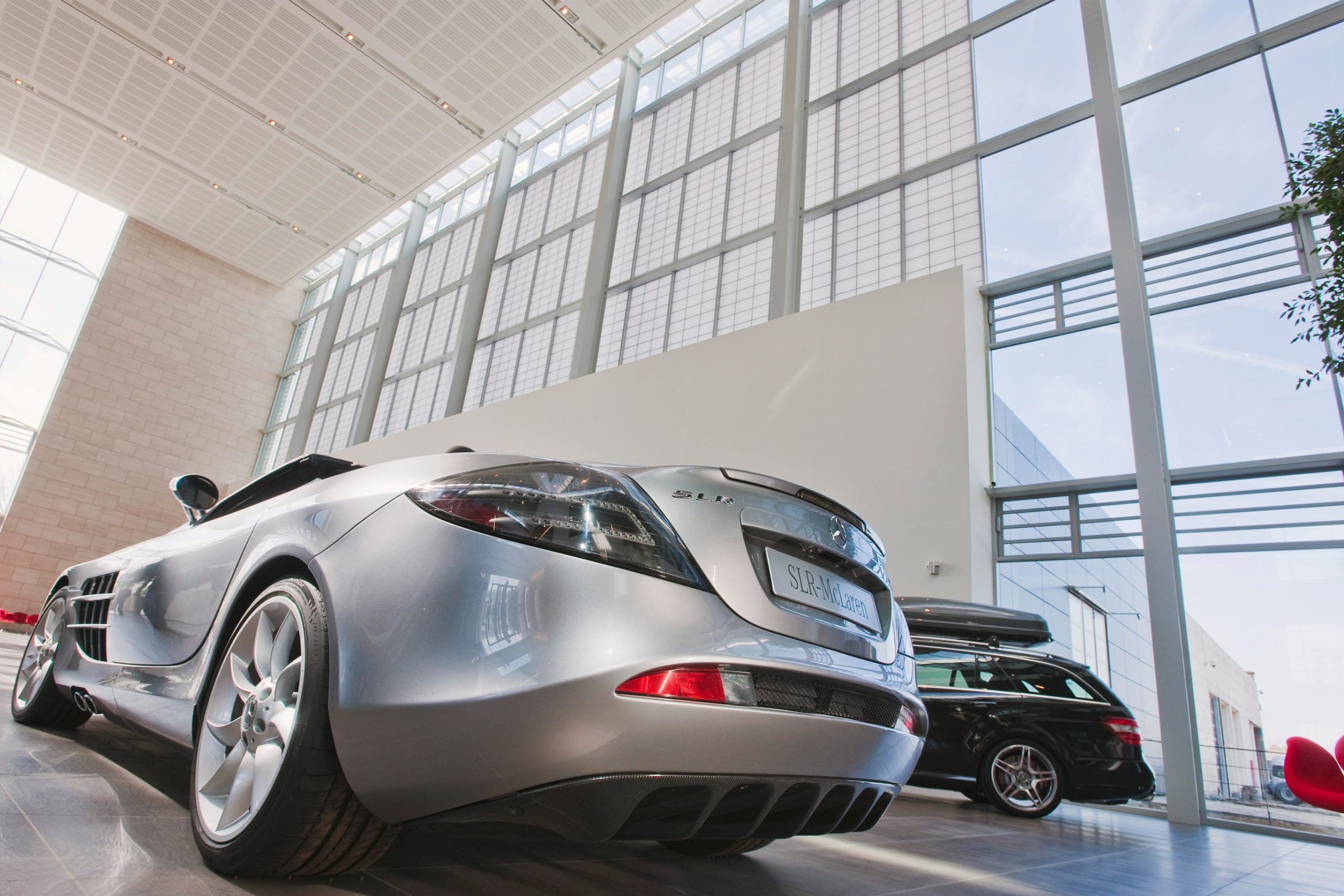 Mercedes Benz facility interior looking at two cars with Kalwall wall panel facade offering translucent daylighting above