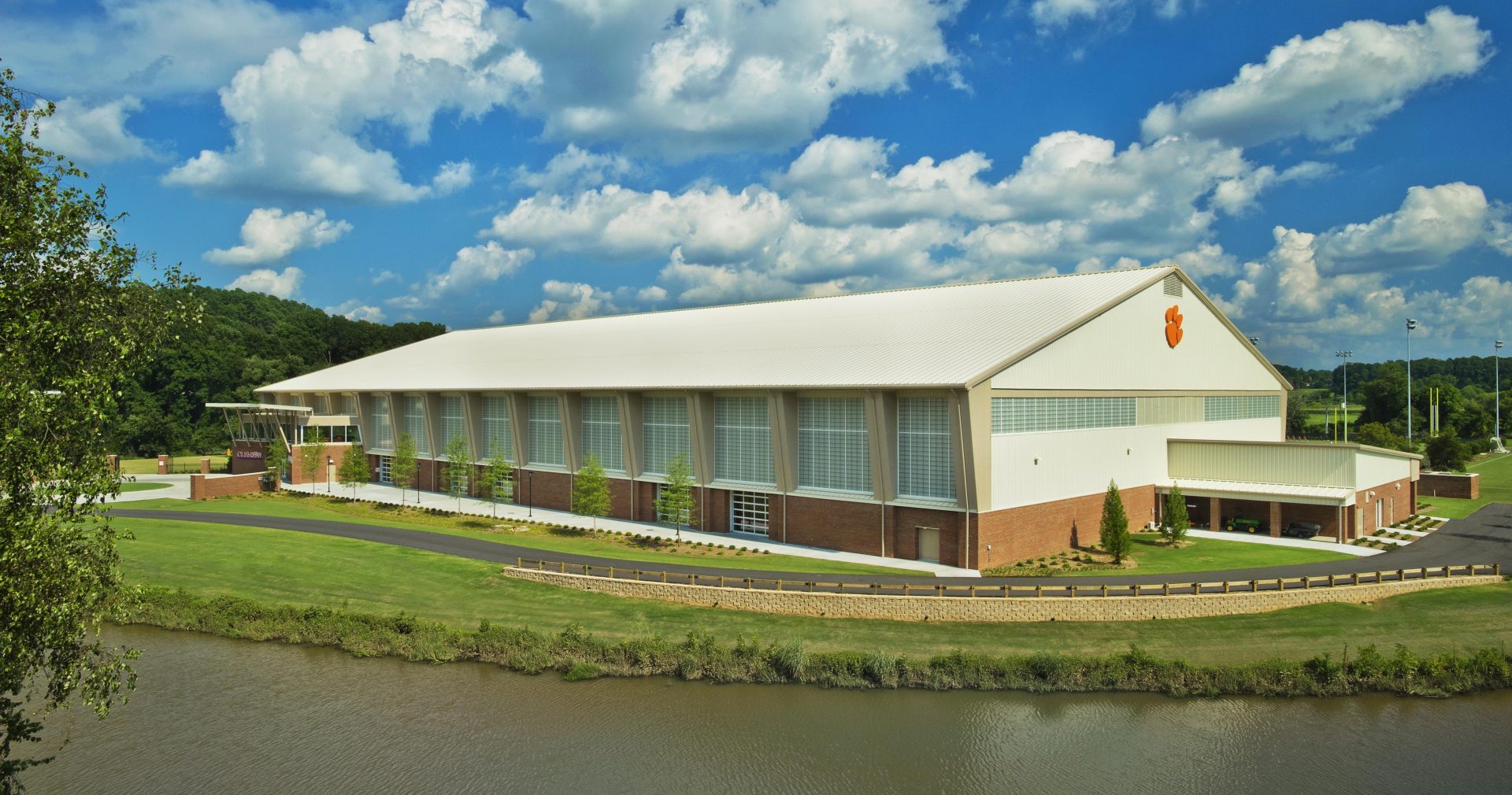 Clemson indoor football practice facility exterior under blue sky with clouds featuring wall of Kalwall translucent facades