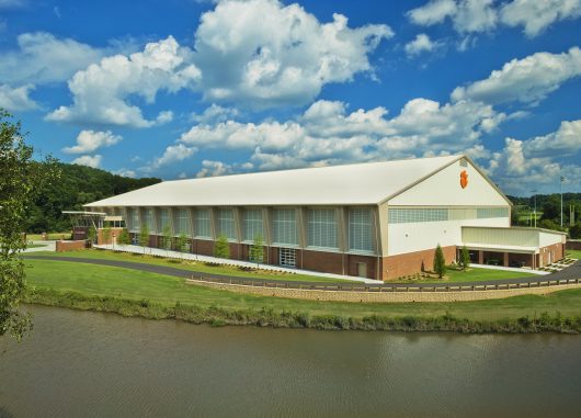 Clemson indoor football practice facility exterior under blue sky with clouds featuring wall of Kalwall translucent facades