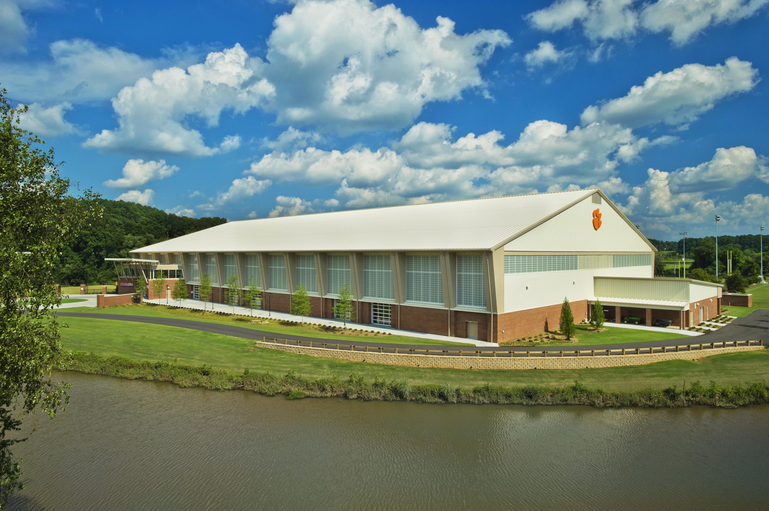 Clemson indoor football practice facility exterior under blue sky with clouds featuring wall of Kalwall translucent facades