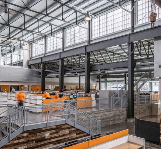 Industrial building featuring Kalwall facade on upper third of wall and employees in orange uniforms