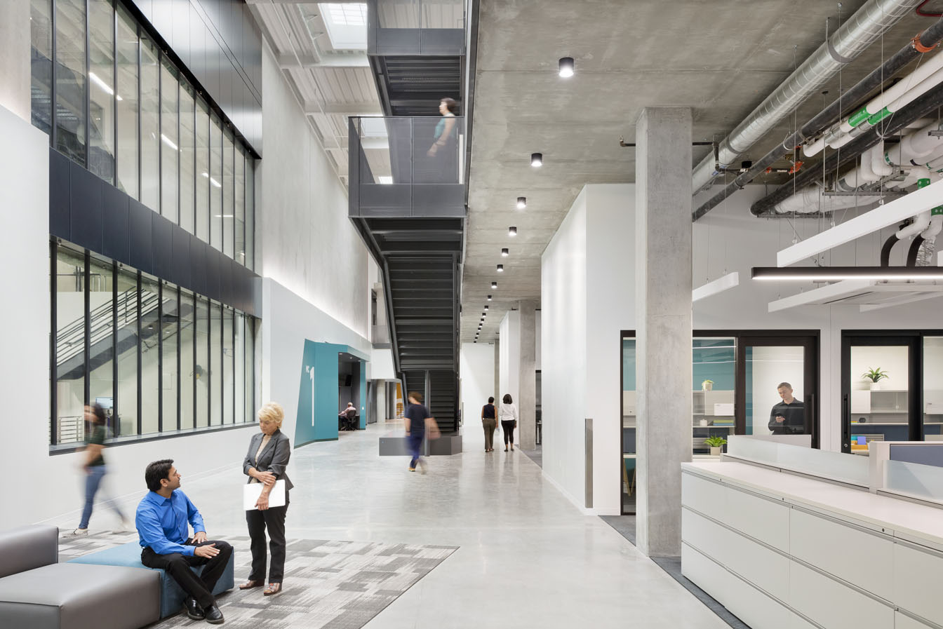 Interior of California Air Resources Board lobby filled with people, a staircase and interior windows.