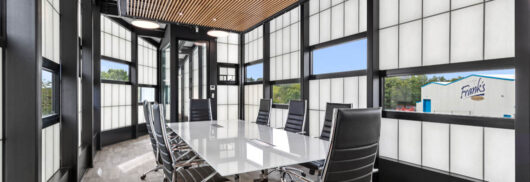 Interior of the Frank's Ice Cream office with a conference table and chairs set among a Kalwall facade with unitized windows.