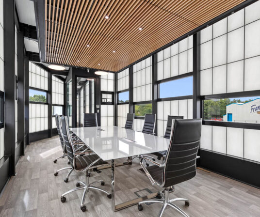 Interior of the Frank's Ice Cream office with a conference table and chairs set among a Kalwall facade with unitized windows.