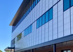 Modern architectural facade of McCauley Mercy Care Center featuring Kalwall's daylight-enhancing curtainwall system, showcasing large windows and a sleek design against a clear blue sky.