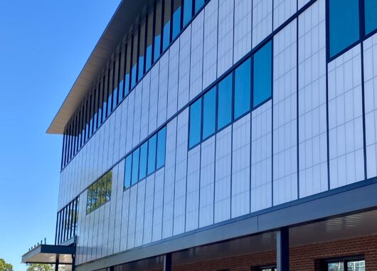 Modern architectural facade of McCauley Mercy Care Center featuring Kalwall's daylight-enhancing curtainwall system, showcasing large windows and a sleek design against a clear blue sky.
