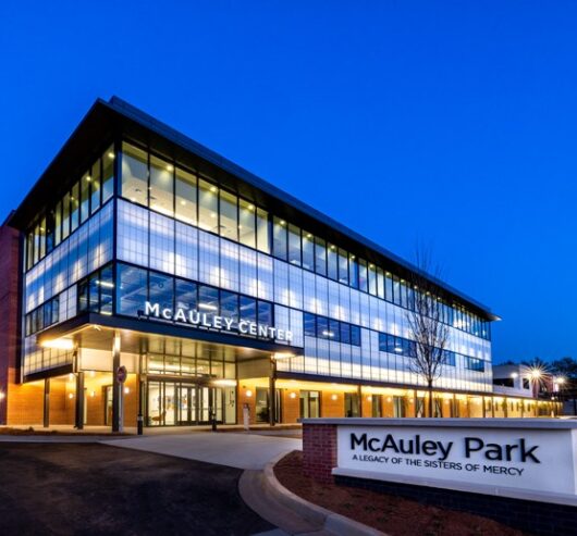 McAuley Center at McAuley Park, showcasing Kalwall's daylighting design, modern architecture, and illuminated entrance at dusk.